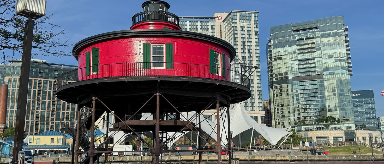 Seven Foot Knoll Lighthouse at Baltimore's Inner Harbor, a red iron lighthouse on pilings in front of glass office towers.